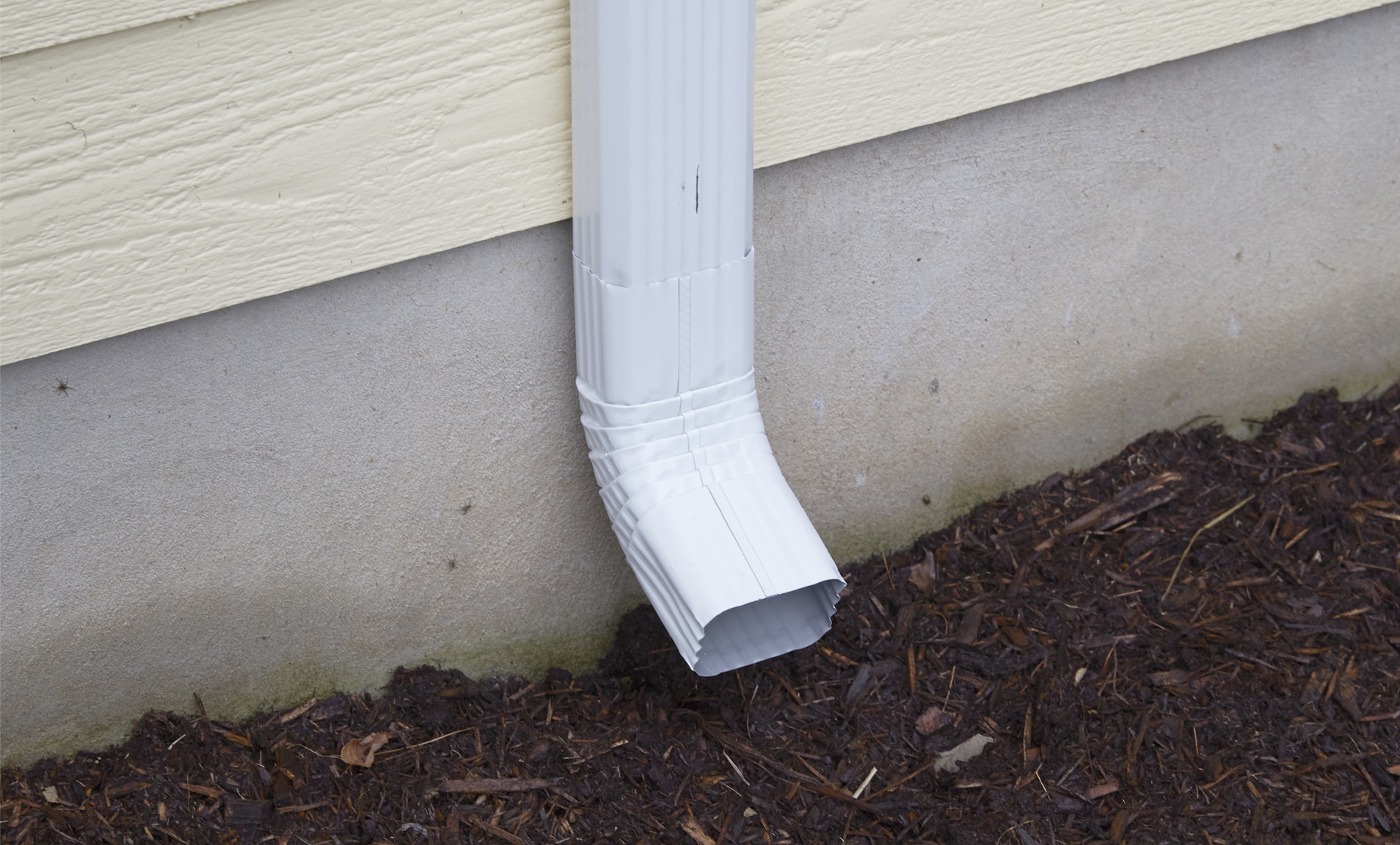 A downspout on a new gutter installed by Built Strong Exteriors.